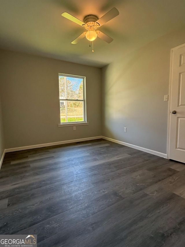 empty room featuring ceiling fan, dark wood-type flooring, and baseboards