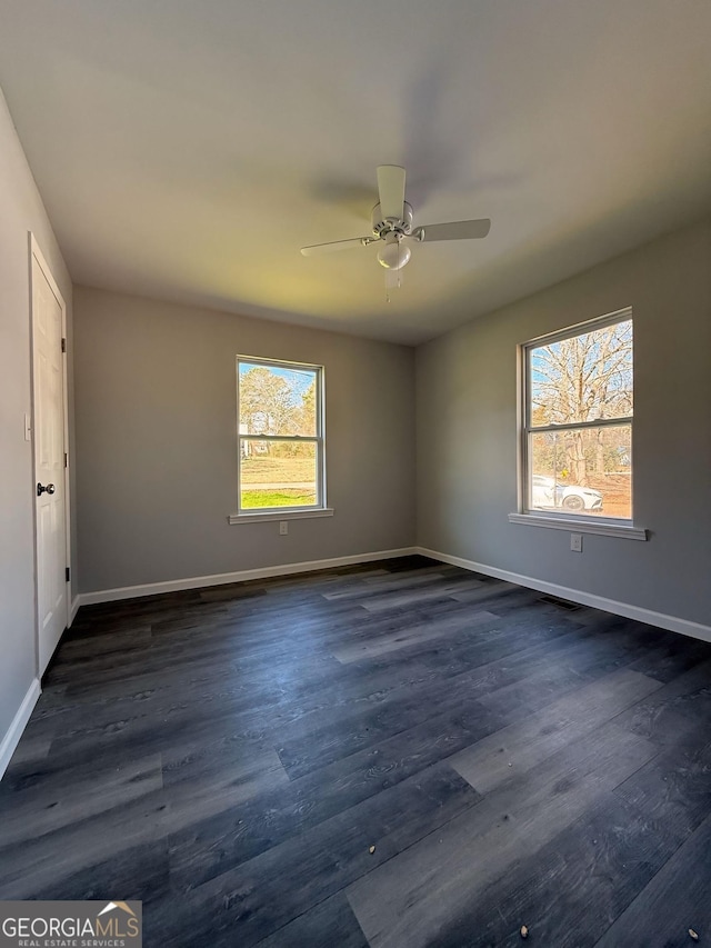 unfurnished bedroom with multiple windows, baseboards, and dark wood-type flooring