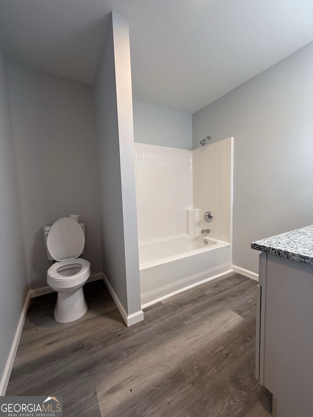 full bathroom featuring shower / bathing tub combination, toilet, vanity, wood finished floors, and baseboards