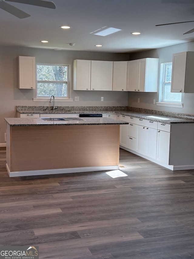 kitchen featuring stone counters, white cabinetry, a kitchen island, and ceiling fan