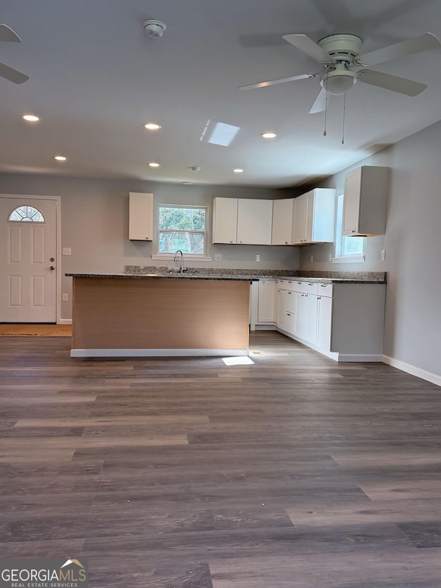 kitchen with dark stone counters, dark wood-style flooring, a sink, and white cabinetry