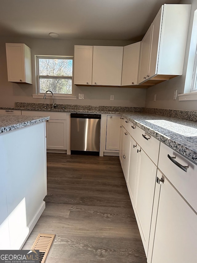 kitchen with stone counters, visible vents, stainless steel dishwasher, white cabinetry, and a sink