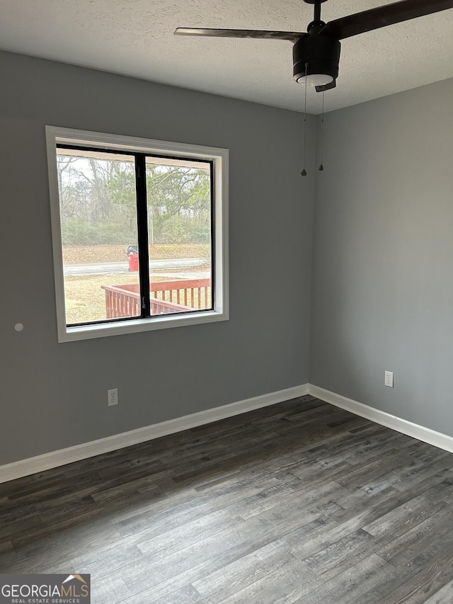 unfurnished room with ceiling fan, a textured ceiling, baseboards, and dark wood-style flooring