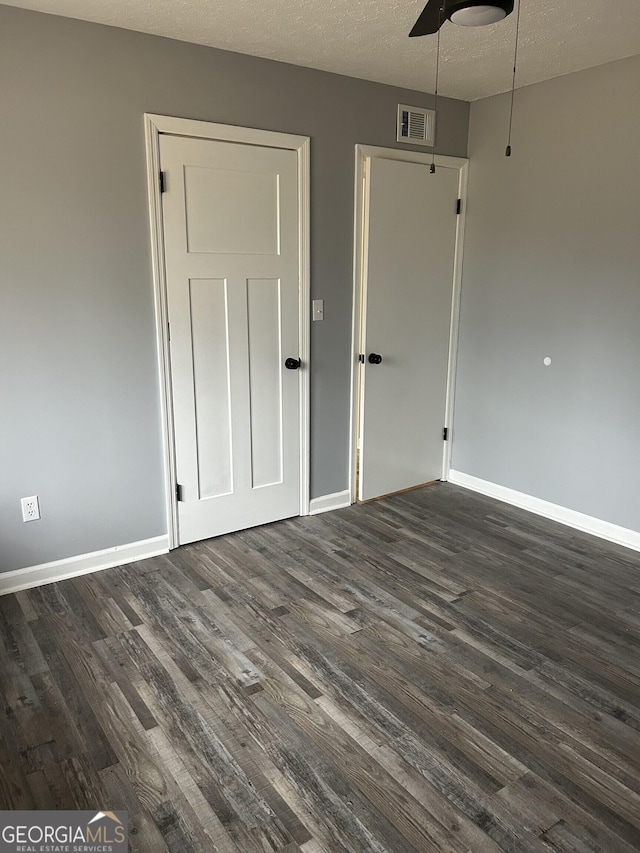 interior space with baseboards, visible vents, ceiling fan, dark wood-style flooring, and a textured ceiling