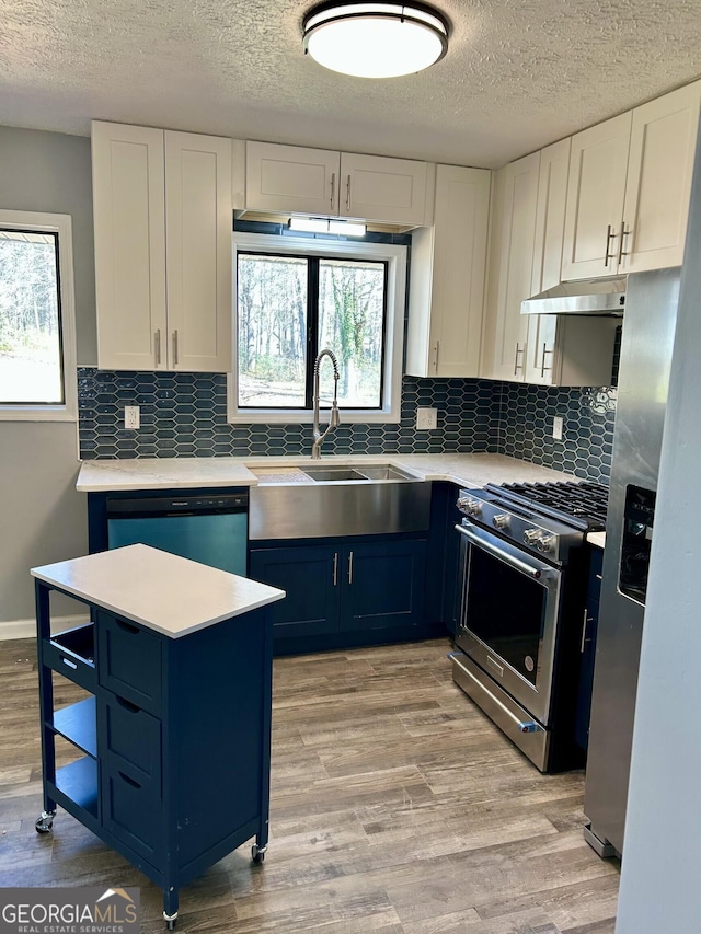 kitchen with stainless steel appliances, white cabinets, light countertops, and light wood finished floors