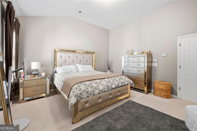 bedroom featuring vaulted ceiling, baseboards, visible vents, and light colored carpet