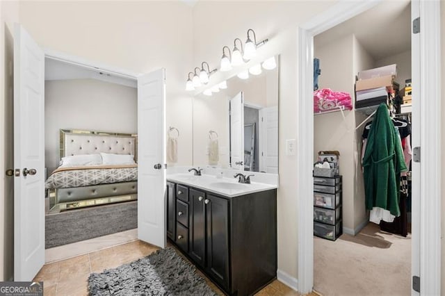 full bath with double vanity, a spacious closet, ensuite bathroom, a sink, and tile patterned flooring