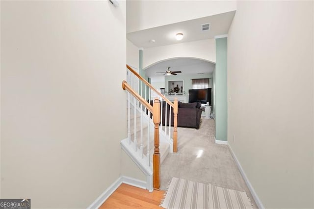 corridor with arched walkways, stairway, visible vents, and baseboards