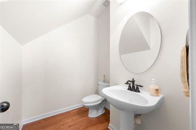 bathroom featuring vaulted ceiling, wood finished floors, toilet, and baseboards