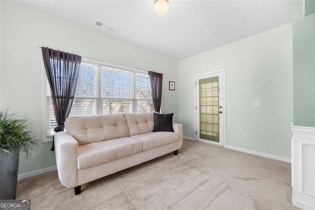 living area featuring baseboards, visible vents, and light colored carpet