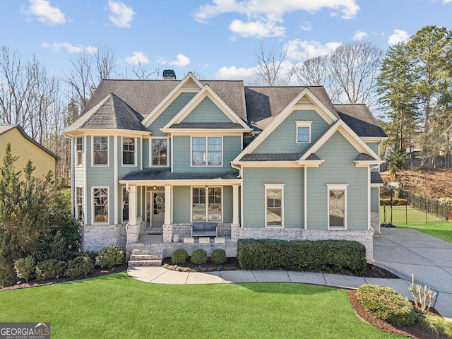 view of front of house featuring a front lawn, a chimney, a porch, and a shingled roof