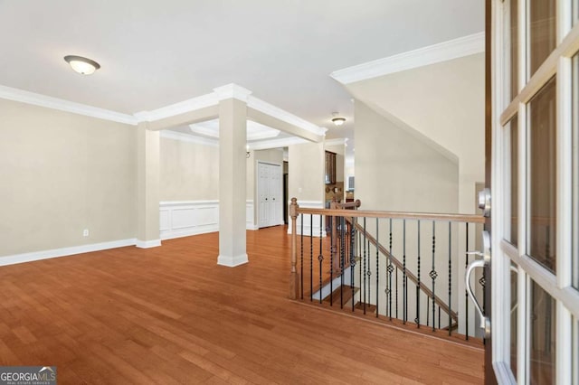 interior space featuring baseboards, wood finished floors, an upstairs landing, and crown molding