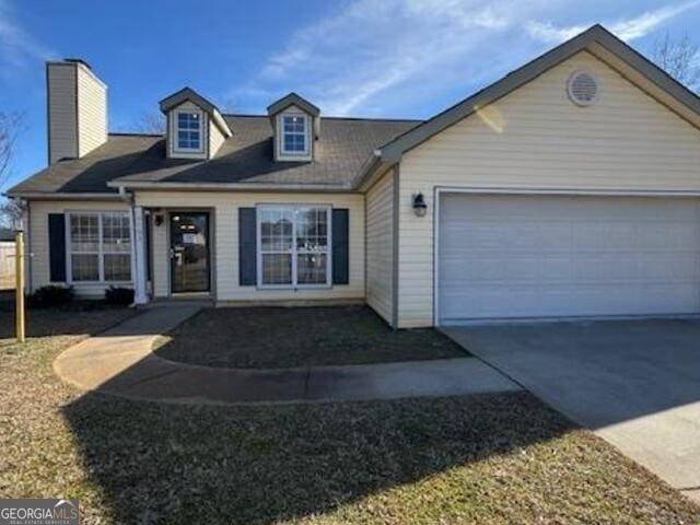 view of front of home featuring driveway, a garage, and a chimney