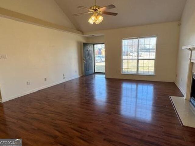 unfurnished living room featuring dark wood finished floors, a ceiling fan, a high end fireplace, high vaulted ceiling, and baseboards