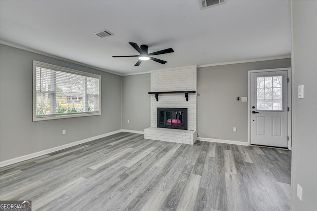 unfurnished living room with plenty of natural light, crown molding, and light wood finished floors