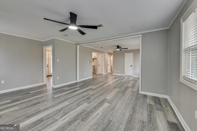 unfurnished living room featuring ornamental molding, light wood-style flooring, visible vents, and baseboards