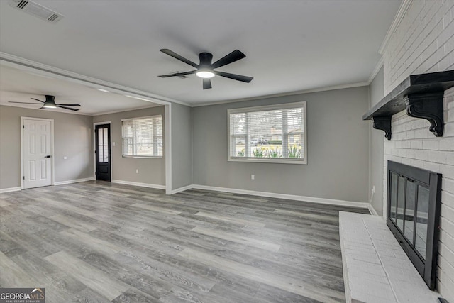 unfurnished living room featuring a brick fireplace, visible vents, crown molding, and wood finished floors