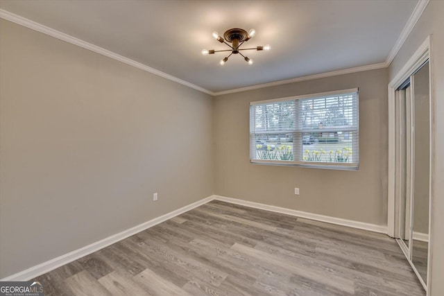 unfurnished bedroom featuring crown molding, a closet, wood finished floors, and baseboards