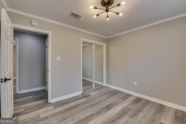 unfurnished bedroom featuring ornamental molding, visible vents, baseboards, and wood finished floors