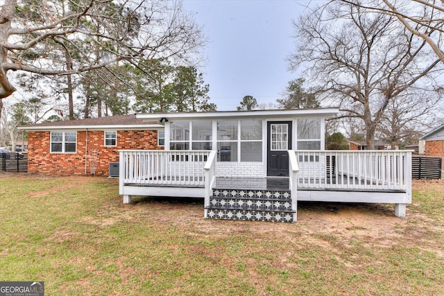 back of house with a sunroom, brick siding, a lawn, and a wooden deck