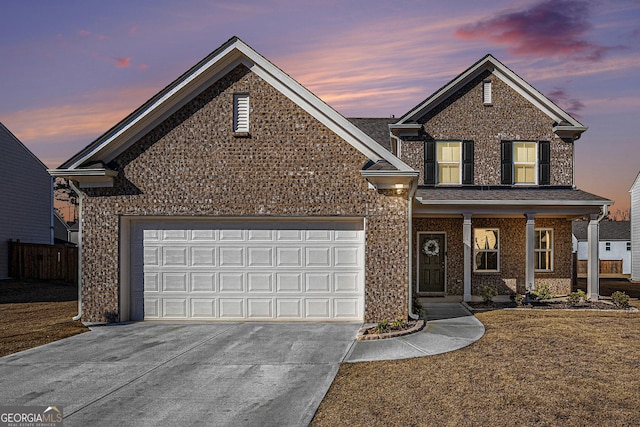 traditional-style house with a garage, concrete driveway, and brick siding