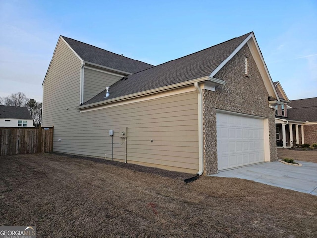 view of property exterior featuring a garage, concrete driveway, fence, and a shingled roof