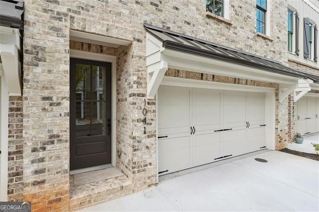 doorway to property with a garage, metal roof, brick siding, and a standing seam roof