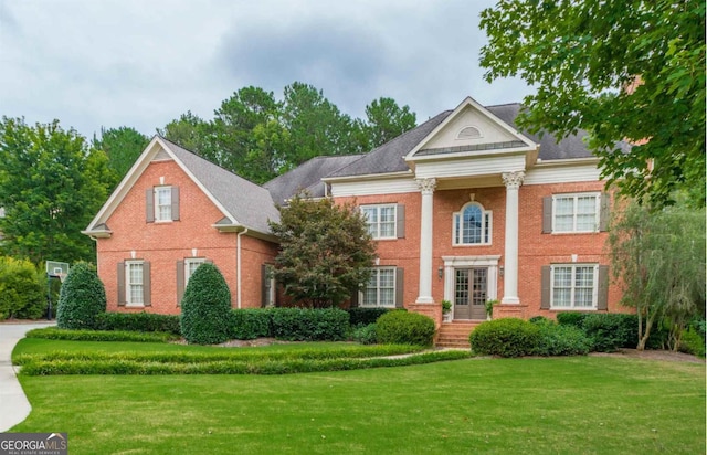 neoclassical home featuring brick siding and a front lawn