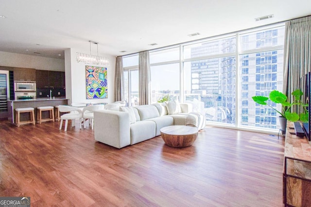 living area with visible vents, a view of city, floor to ceiling windows, and wood finished floors