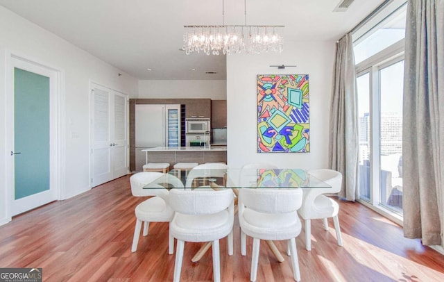 dining room with baseboards, visible vents, a notable chandelier, and light wood finished floors