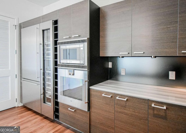 kitchen with light wood-style floors, modern cabinets, stainless steel appliances, and light countertops