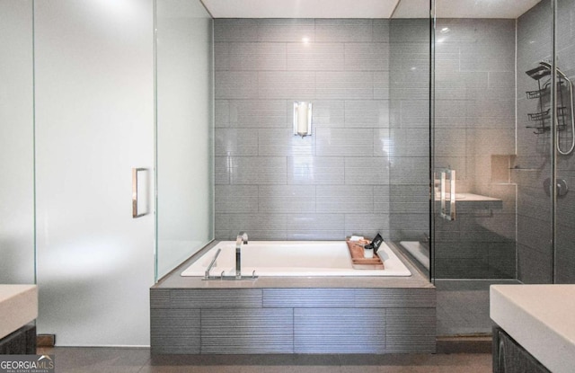 full bathroom with a shower stall, a bath, and vanity