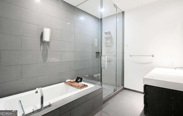 bathroom with a stall shower, baseboards, a bath, and vanity