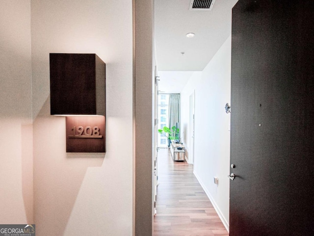 hallway featuring light wood finished floors, visible vents, and baseboards