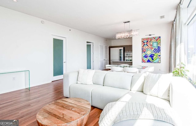 living room with wood finished floors, visible vents, and baseboards