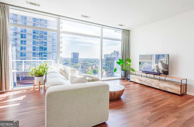 living room featuring wood finished floors, visible vents, and floor to ceiling windows