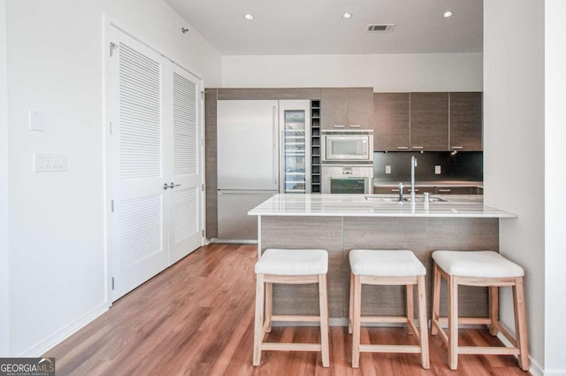 kitchen featuring light countertops, a breakfast bar, modern cabinets, and a peninsula