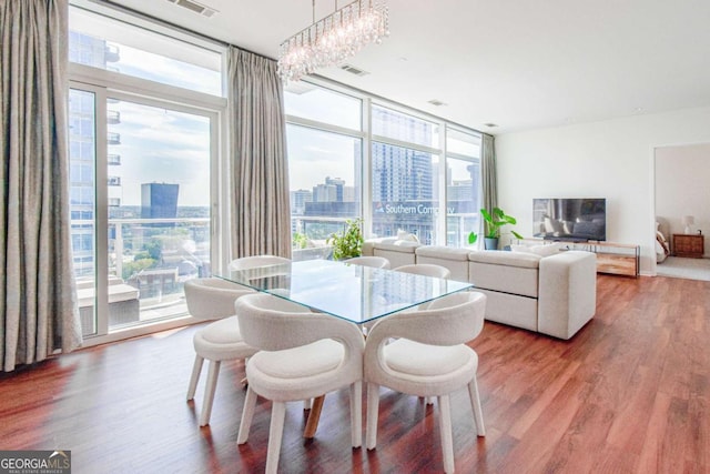 dining area featuring an inviting chandelier, visible vents, floor to ceiling windows, and wood finished floors