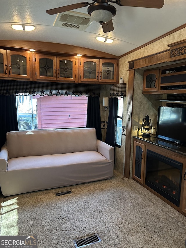 living area featuring lofted ceiling, wallpapered walls, ceiling fan, and visible vents