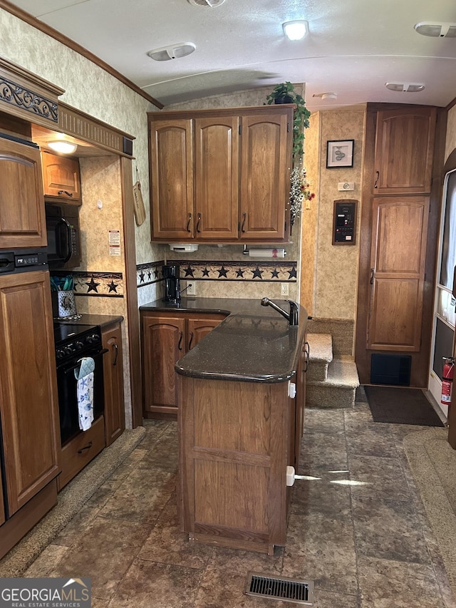 kitchen with visible vents, a kitchen island, black microwave, oven, and wallpapered walls