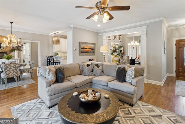 living room featuring crown molding, ceiling fan with notable chandelier, light wood-type flooring, and baseboards