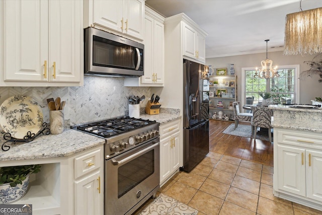 kitchen with light stone countertops, appliances with stainless steel finishes, white cabinets, and pendant lighting