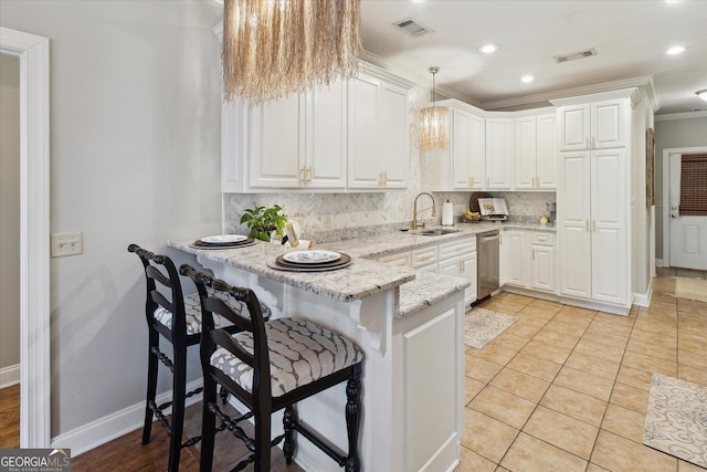 kitchen with pendant lighting, visible vents, white cabinets, a sink, and a peninsula