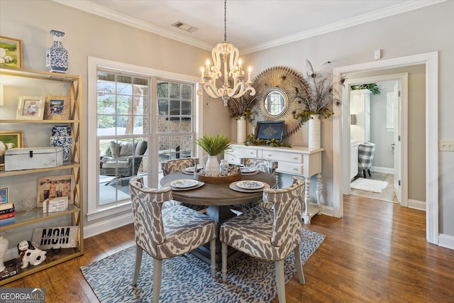 dining room featuring baseboards, visible vents, ornamental molding, dark wood-type flooring, and an inviting chandelier