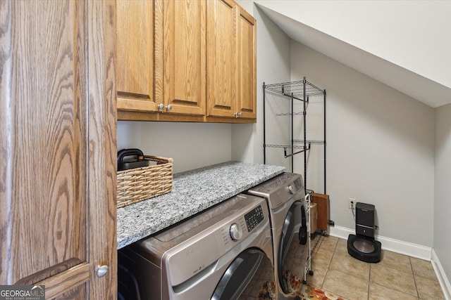 clothes washing area with cabinet space, washing machine and dryer, baseboards, and light tile patterned flooring