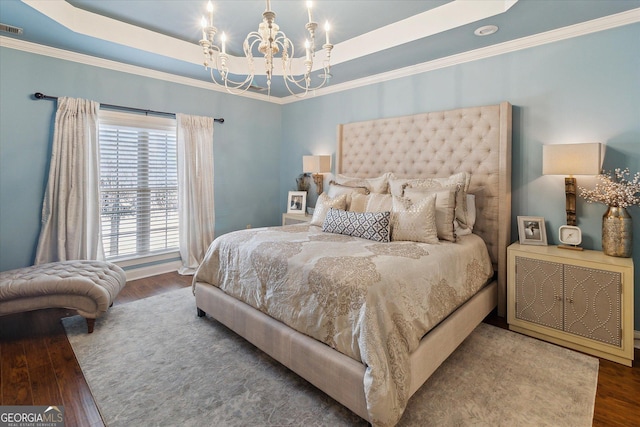 bedroom featuring a notable chandelier, a tray ceiling, wood finished floors, and ornamental molding