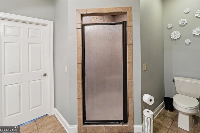 full bath featuring toilet, a stall shower, baseboards, and tile patterned floors