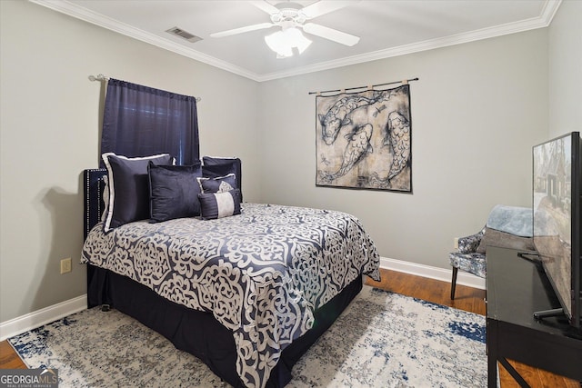 bedroom with ornamental molding, wood finished floors, visible vents, and baseboards