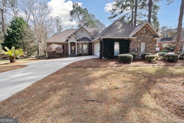 view of front of property with roof with shingles, an attached garage, stone siding, driveway, and a front lawn