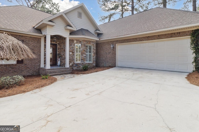 view of front facade featuring a garage, driveway, brick siding, and a shingled roof